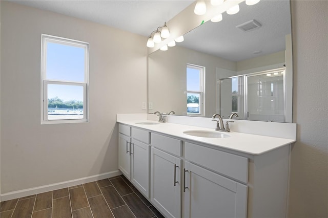 bathroom with vanity and a shower with door