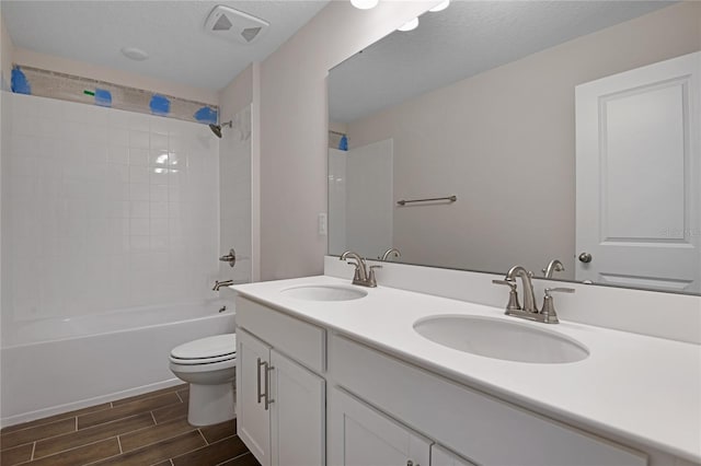 full bathroom with vanity, shower / bath combination, a textured ceiling, and toilet