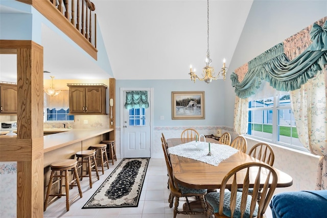 tiled dining area featuring high vaulted ceiling and an inviting chandelier