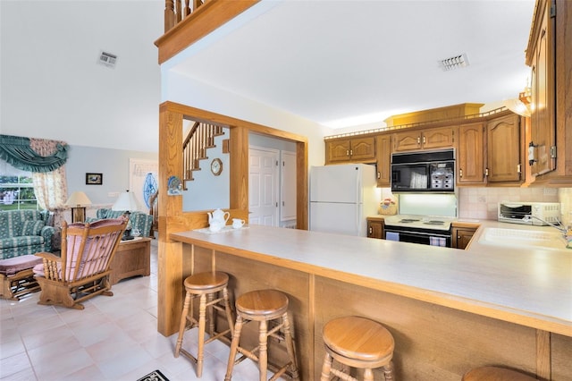 kitchen with a kitchen breakfast bar, backsplash, sink, white appliances, and kitchen peninsula