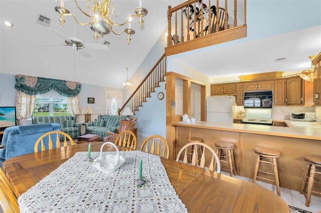 dining space featuring ceiling fan with notable chandelier and a towering ceiling