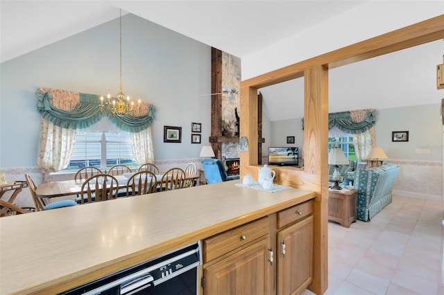 kitchen with light tile patterned flooring, a large fireplace, a chandelier, and lofted ceiling