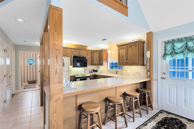 kitchen with a breakfast bar, white appliances, tasteful backsplash, light tile patterned floors, and kitchen peninsula