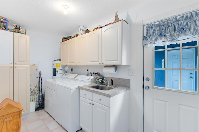 washroom with sink, electric water heater, cabinets, washer and dryer, and light tile patterned floors