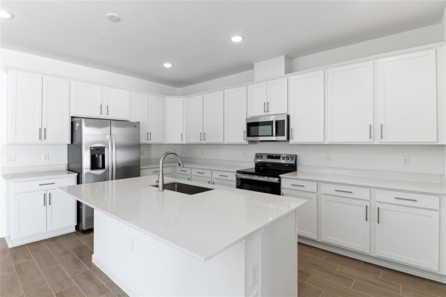 kitchen featuring a kitchen island with sink, sink, white cabinets, and appliances with stainless steel finishes