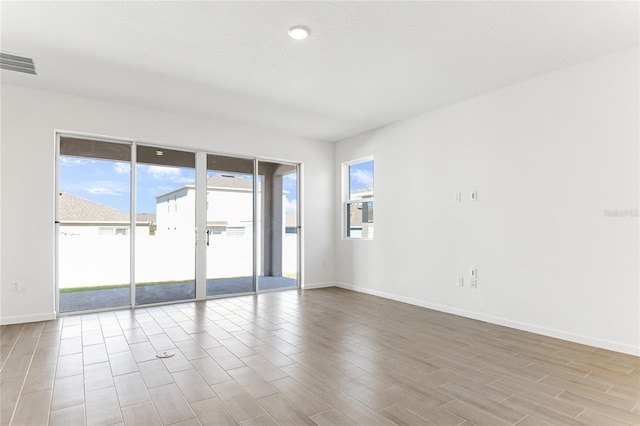 empty room with a textured ceiling and light hardwood / wood-style floors