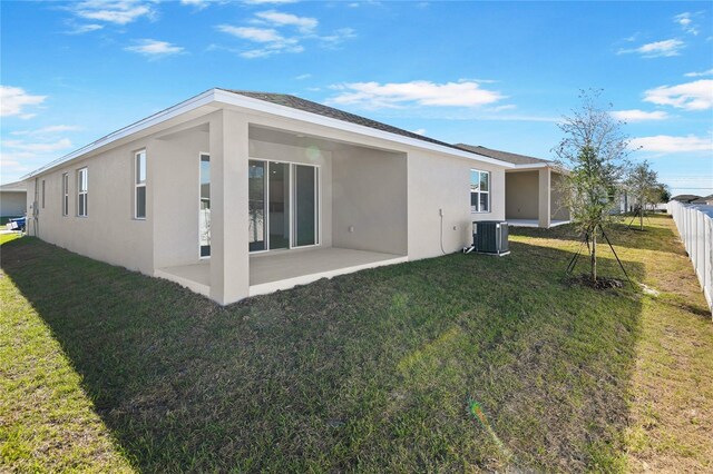 rear view of property with a patio area, central air condition unit, and a lawn