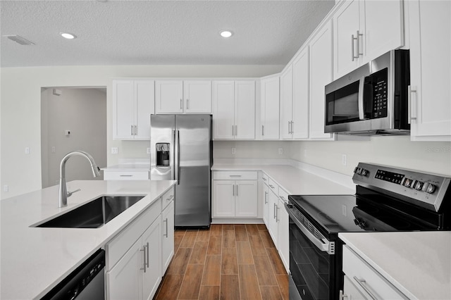 kitchen with appliances with stainless steel finishes, sink, white cabinetry, and a textured ceiling