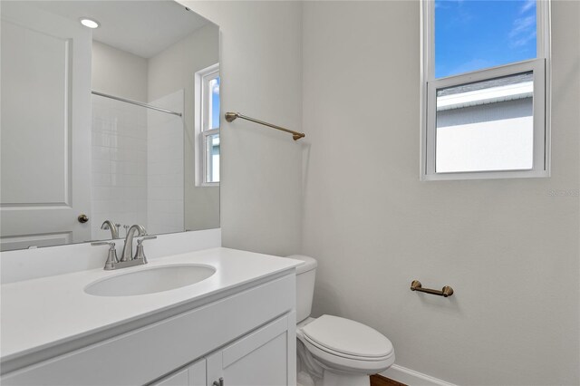 bathroom featuring toilet, vanity, and plenty of natural light