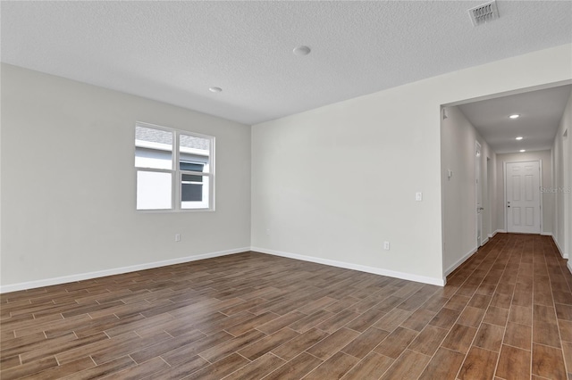 spare room with a textured ceiling and dark wood-type flooring