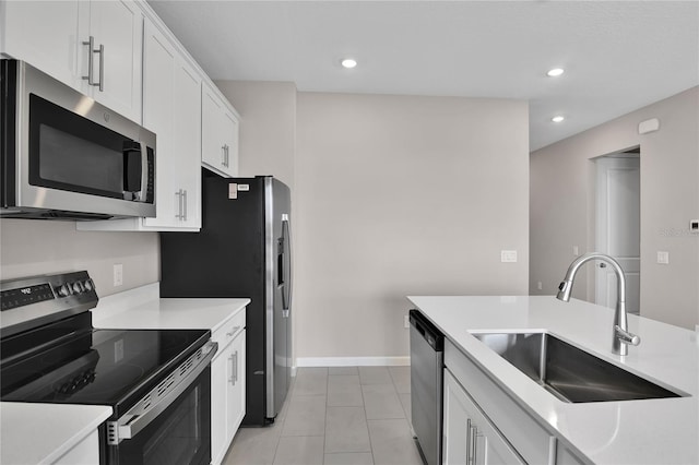 kitchen with appliances with stainless steel finishes, sink, light tile patterned floors, and white cabinets