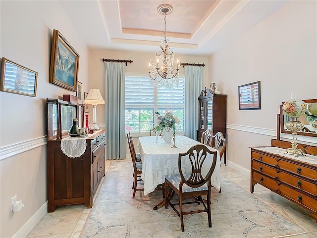 tiled dining space with a raised ceiling and a chandelier