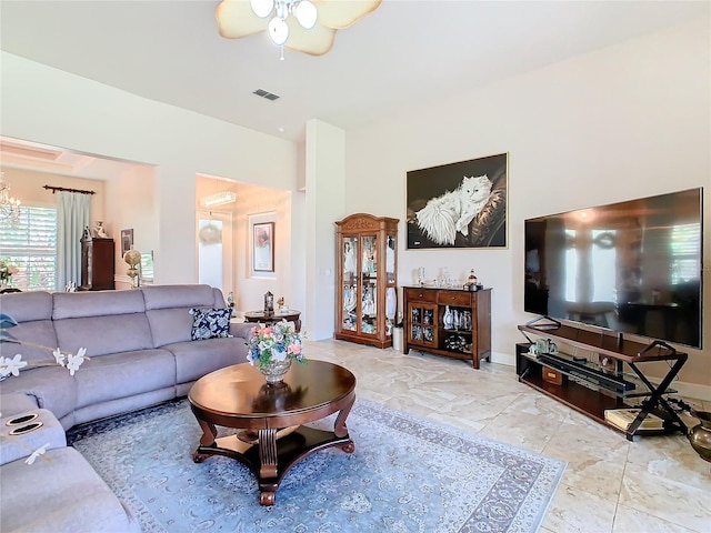 living room with ceiling fan with notable chandelier and light tile patterned floors