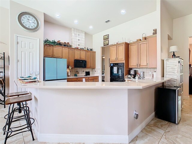 kitchen with black appliances, backsplash, a kitchen breakfast bar, and light tile patterned floors