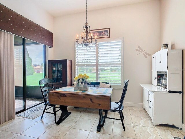 dining room with a notable chandelier, light tile patterned floors, and a high ceiling