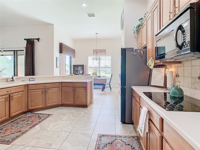 kitchen with decorative backsplash, black appliances, a notable chandelier, light tile patterned floors, and decorative light fixtures