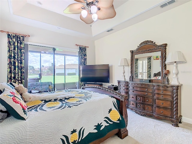 bedroom featuring ceiling fan, a raised ceiling, carpet, and access to exterior