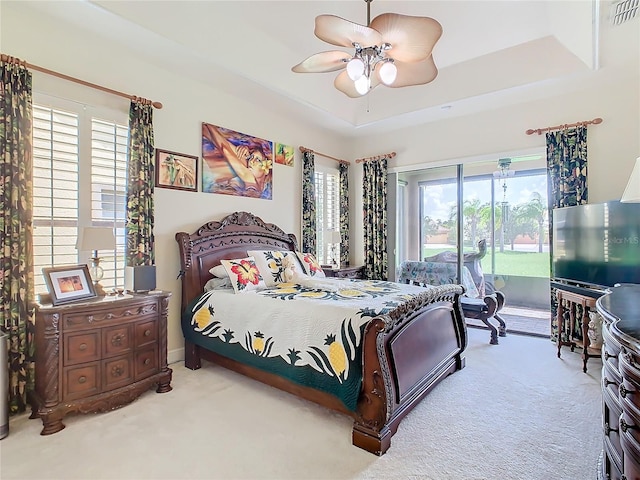 bedroom featuring carpet flooring, a tray ceiling, and multiple windows