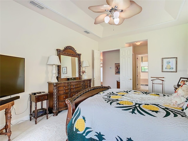 bedroom with ceiling fan, a raised ceiling, and light carpet