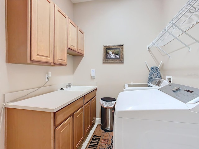 washroom with cabinets, sink, and independent washer and dryer