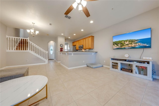 tiled living room with ceiling fan with notable chandelier