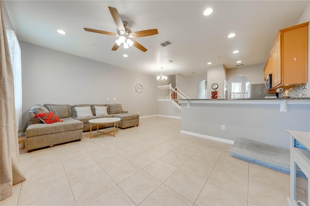 tiled living room featuring ceiling fan with notable chandelier