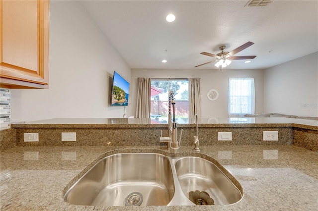 kitchen featuring light brown cabinetry, tasteful backsplash, ceiling fan, sink, and light stone counters