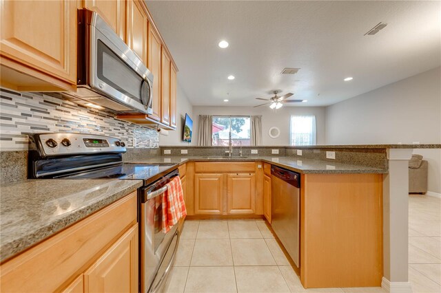 kitchen featuring appliances with stainless steel finishes, tasteful backsplash, light tile patterned floors, and ceiling fan