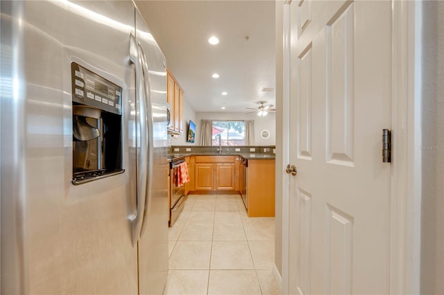 kitchen with light tile patterned floors, kitchen peninsula, ceiling fan, appliances with stainless steel finishes, and sink