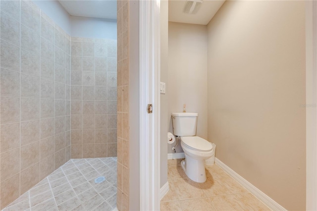 bathroom with tile patterned floors, toilet, and a tile shower