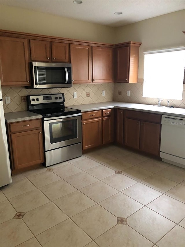 kitchen with backsplash, light tile patterned floors, sink, and appliances with stainless steel finishes