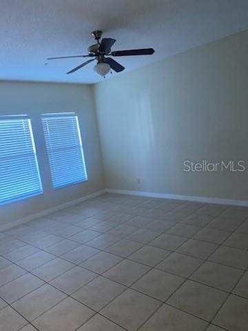 tiled spare room featuring ceiling fan