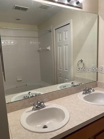 bathroom featuring vanity, bathtub / shower combination, and a textured ceiling