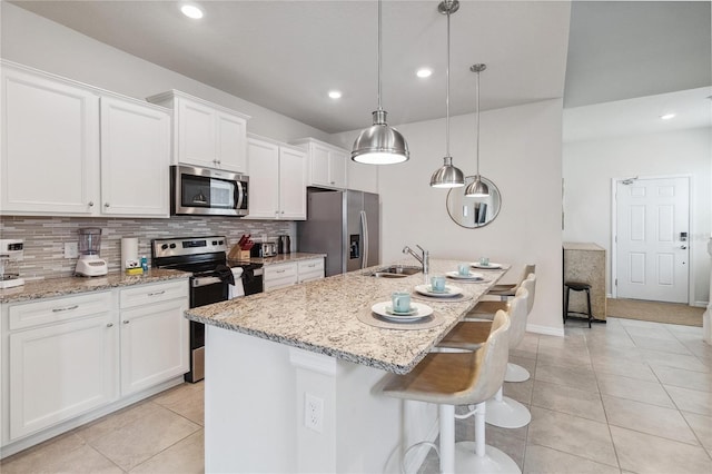 kitchen with appliances with stainless steel finishes, decorative backsplash, and an island with sink