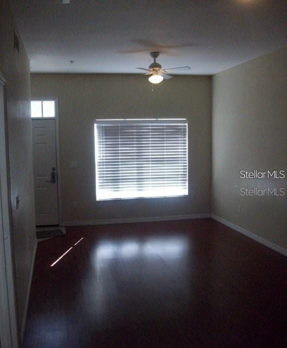 empty room with ceiling fan and dark wood-type flooring