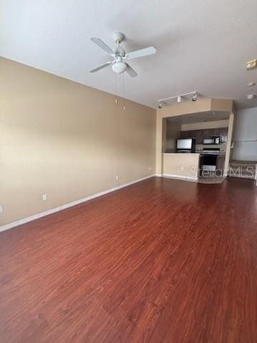 unfurnished living room featuring track lighting, ceiling fan, and dark hardwood / wood-style floors