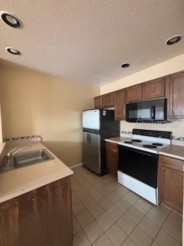 kitchen featuring light tile patterned flooring, white range with electric cooktop, and stainless steel fridge