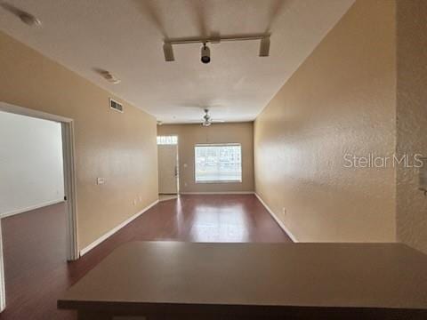 empty room with track lighting, hardwood / wood-style floors, and ceiling fan