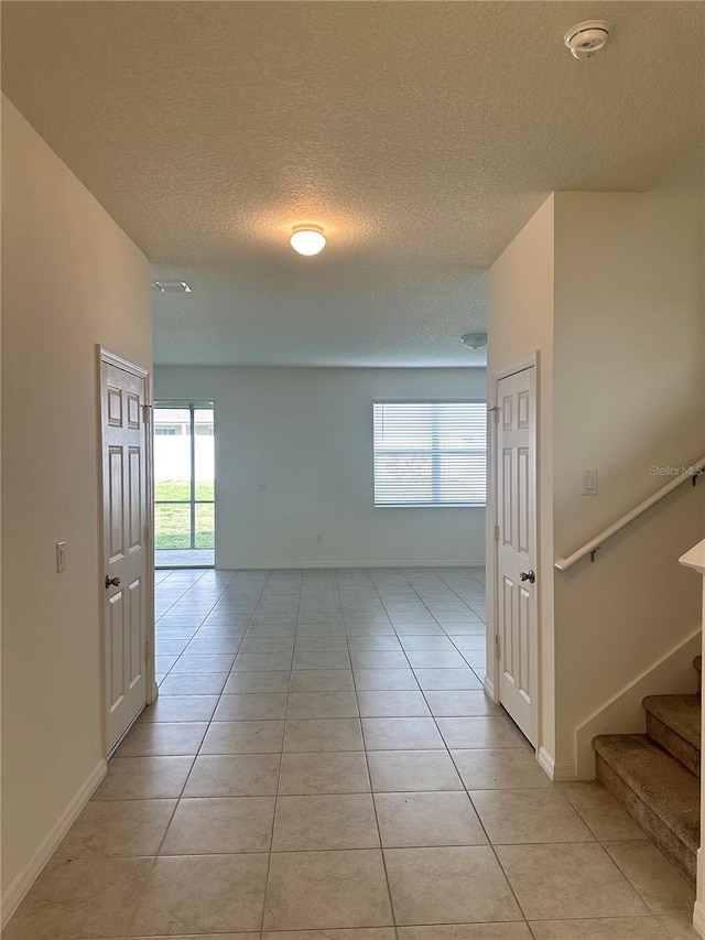 corridor with light tile patterned floors and a textured ceiling