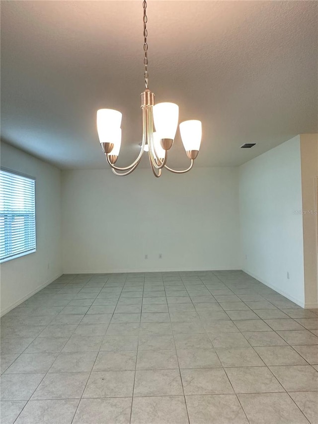 tiled empty room featuring a notable chandelier