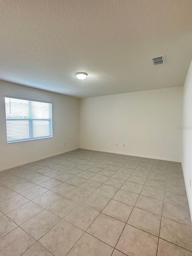 spare room featuring a textured ceiling and light tile patterned floors