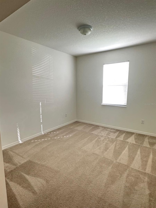 carpeted spare room with a textured ceiling