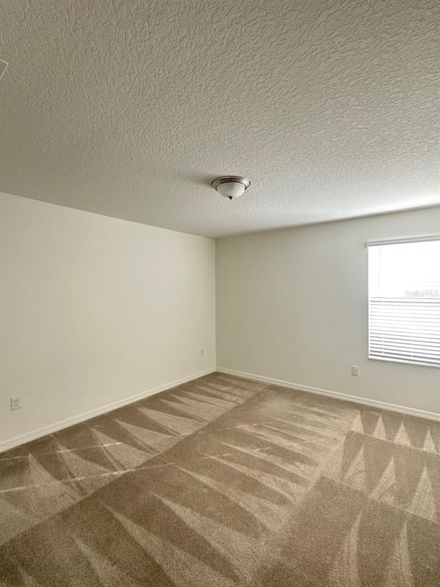 carpeted empty room with a textured ceiling