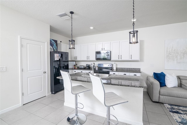 kitchen with a breakfast bar, light tile patterned floors, white cabinets, an island with sink, and black appliances