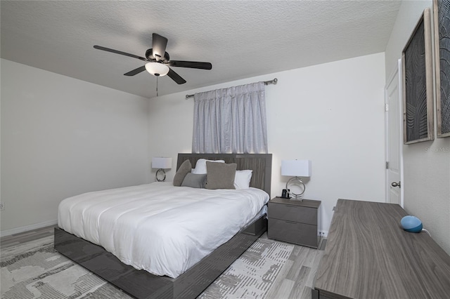 bedroom with a textured ceiling, ceiling fan, and light wood-type flooring