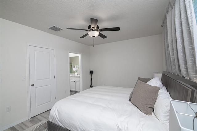 bedroom with a textured ceiling, light hardwood / wood-style flooring, ensuite bath, and ceiling fan