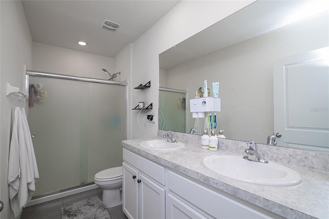 bathroom featuring a shower with shower door, tile patterned floors, toilet, and double sink vanity