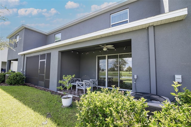 back of property with a lawn and ceiling fan