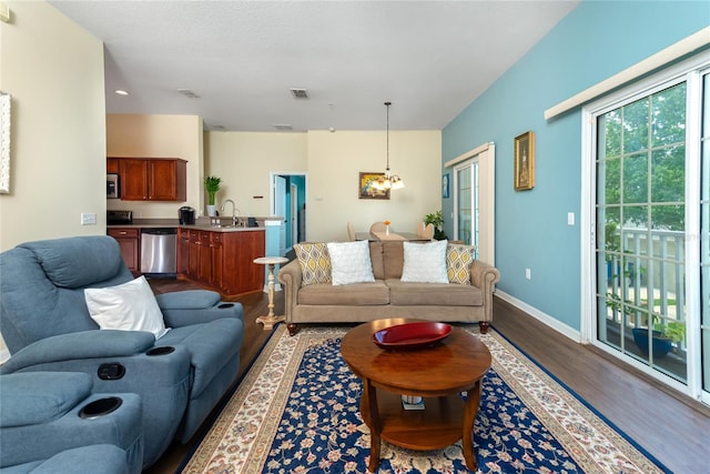 living room with sink, an inviting chandelier, and hardwood / wood-style floors