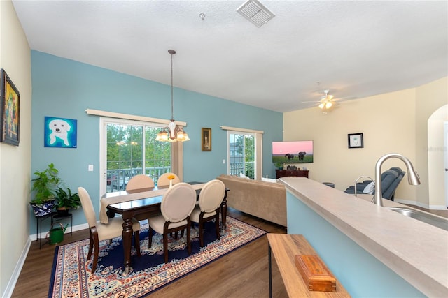 dining area with sink, dark wood-type flooring, ceiling fan with notable chandelier, and a textured ceiling